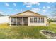 Tan house exterior with a large screened porch and landscaped yard at 3200 Woodridge Dr, The Villages, FL 32162