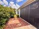 Exterior view of patio with outdoor screen, mulched flower bed, and paver path at 3554 Oracle Ct, The Villages, FL 32163