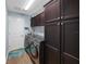 Laundry room features dark brown cabinets, modern washer and dryer, and wood-look flooring at 4442 Shannon Loop, The Villages, FL 32163