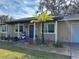 Tan house with blue roof, white columns, landscaping, and a walkway at 8202 Oak St, Yalaha, FL 34797