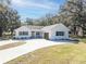 Charming farmhouse-style home with a large driveway and mature trees at 871 Cr 548, Bushnell, FL 33513