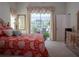 Bright bedroom with red floral bedding and access to a patio at 10108 Silver Bluff Dr, Leesburg, FL 34788