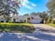 Single-story house with attached garage, lush lawn, and mature trees at 10108 Silver Bluff Dr, Leesburg, FL 34788