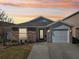Charming single-story home with brick accents, attached garage, and well-maintained lawn against a colorful sunset sky at 12306 Ne 48Th Way, Oxford, FL 34484