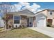 One-story house with stone exterior, white garage door, and landscaping at 12306 Ne 48Th Way, Oxford, FL 34484