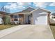 Attractive home featuring a stone facade, manicured lawn, and convenient attached garage at 12306 Ne 48Th Way, Oxford, FL 34484