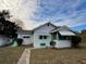 Front view of a cozy white house with a green awning and well-maintained lawn at 13920 S Highway 25, Eastlake Weir, FL 32133