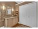 Bathroom featuring a light wood vanity with stone countertop, a decorative mirror, and ample storage space at 16967 Se 93Rd Cuthbert Cir, The Villages, FL 32162