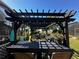 View of backyard pergola featuring an outdoor kitchen, dining area, and decorative string lights at 17430 Se 115Th Terrace Rd, Summerfield, FL 34491