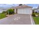 A decorative driveway leads to a tan house with a garage at 2240 Avon Loop, The Villages, FL 32162