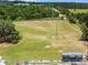 Aerial view of a lush golf course, showcasing its expansive green fairways, practice facilities, and wooded surroundings at 25941 Newcombe Cir, Leesburg, FL 34748