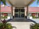 Exterior shot of a building entrance with symmetrical architecture, lush landscaping, and a covered walkway at 25941 Newcombe Cir, Leesburg, FL 34748