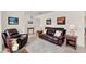 Elegant living room featuring tile flooring, a comfortable leather sofa and matching recliner at 25941 Newcombe Cir, Leesburg, FL 34748