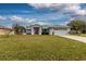 Single-story home with a red door, attached garage, and well-manicured lawn at 27302 Orchid Glade St, Leesburg, FL 34748