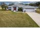 Single-story home with gray siding, red door, and two-car garage, nicely landscaped yard at 27302 Orchid Glade St, Leesburg, FL 34748