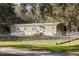 Tan mobile home with chain link fence and grassy yard at 3704 Warm Springs Ave, Wildwood, FL 34785