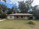 Tan one-story house with brown roof, stone accents, and a covered porch at 403 W Palm Ave, Bushnell, FL 33513