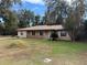 Tan one-story house with brown roof, stone accents, and a covered porch at 403 W Palm Ave, Bushnell, FL 33513