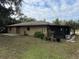 Rear view of tan house with screened porch and patio at 403 W Palm Ave, Bushnell, FL 33513