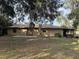 Rear view of tan house with double doors and patio at 403 W Palm Ave, Bushnell, FL 33513