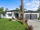 White modern home with dark garage door and landscaped lawn at 42025 Royal Trails Rd, Eustis, FL 32736