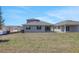 Rear of home showcasing lawn, sliding glass door, and windows; construction is going on in the neighboring lot at 5119 Firebush Dr, Apopka, FL 32712