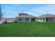 Rear of home showcasing lawn, sliding glass door, and windows; construction is going on in the neighboring lot at 5119 Firebush Dr, Apopka, FL 32712