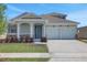 Charming home featuring a two-car garage, covered entryway with columns, stone accents, and freshly manicured lawn at 5119 Firebush Dr, Apopka, FL 32712