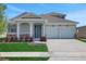 Charming home featuring a two-car garage, covered entryway with columns, stone accents, and freshly manicured lawn at 5119 Firebush Dr, Apopka, FL 32712