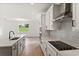 Modern kitchen with white cabinets, stainless steel appliances, and gray backsplash at 5191 Firebrush Dr, Apopka, FL 32712