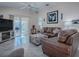 Spacious living room with brown leather sectional and access to lanai at 8480 Se 167Th Forsyth St, The Villages, FL 32162