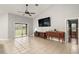 Bright living room with a large TV, tile floors, and view of the dining area at 9320 County Road 125B, Wildwood, FL 34785