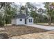 Charming new construction home with black roof, white siding, and driveway, nestled among mature trees at Lot 42 Indian Estates Cr 423, Lake Panasoffkee, FL 33538