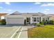 Front view of a white house with green shutters, landscaped lawn, and a two-car garage at 16967 Se 93Rd Cuthbert Cir, The Villages, FL 32162