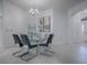 Bright dining room with glass table and four chairs, an elegant chandelier, and modern artwork at 5911 Delphina Loop, The Villages, FL 32163