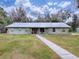 Ranch style home with metal roof and walkway leading to the front entrance at 1029 Cr 452A, Lake Panasoffkee, FL 33538