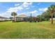 Large backyard with lush green grass and a screened pool at 10377 Silver Maple Ave, Oxford, FL 34484