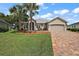 Tan house with palm trees, paver driveway and two-car garage at 10377 Silver Maple Ave, Oxford, FL 34484