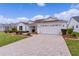 Front view of a white house with a paver driveway and nicely landscaped yard at 1216 Addison Ave, The Villages, FL 32162