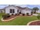 Side view of a white house showcasing the landscaping and a partial view of the driveway at 1216 Addison Ave, The Villages, FL 32162