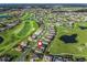 Aerial view of a golf course community with well-maintained homes and lush green fairways and pond at 12213 Se 176Th Loop, Summerfield, FL 34491