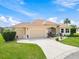 Tan house with a two-car garage and well-maintained lawn at 1276 Bennett Pl, The Villages, FL 32162