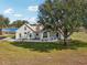 Charming home exterior with a lush lawn, a white picket fence, and mature trees casting shade at 13718 County Road 450, Umatilla, FL 32784