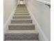 Carpeted staircase leading upstairs with white painted risers and handrail at 13718 County Road 450, Umatilla, FL 32784