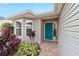 Front entry with teal door and brick walkway at 1548 Loris Loop, The Villages, FL 32162