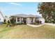 Tan one-story house with teal door and nicely landscaped yard at 1548 Loris Loop, The Villages, FL 32162