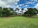 Community entrance sign amidst lush landscaping and palm trees under a partly cloudy sky at 1562 Lawndale Cir, Winter Park, FL 32792