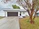 Newly renovated home with white exterior, brown garage door, and landscaped yard at 1562 Lawndale Cir, Winter Park, FL 32792