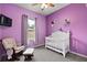 Bedroom with purple walls, white crib, and rocking chair at 16029 Worthington N Blvd, Mascotte, FL 34753