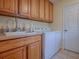 Laundry room with washer, dryer, and wood cabinets at 16841 Se 84Th Colerain Cir, The Villages, FL 32162